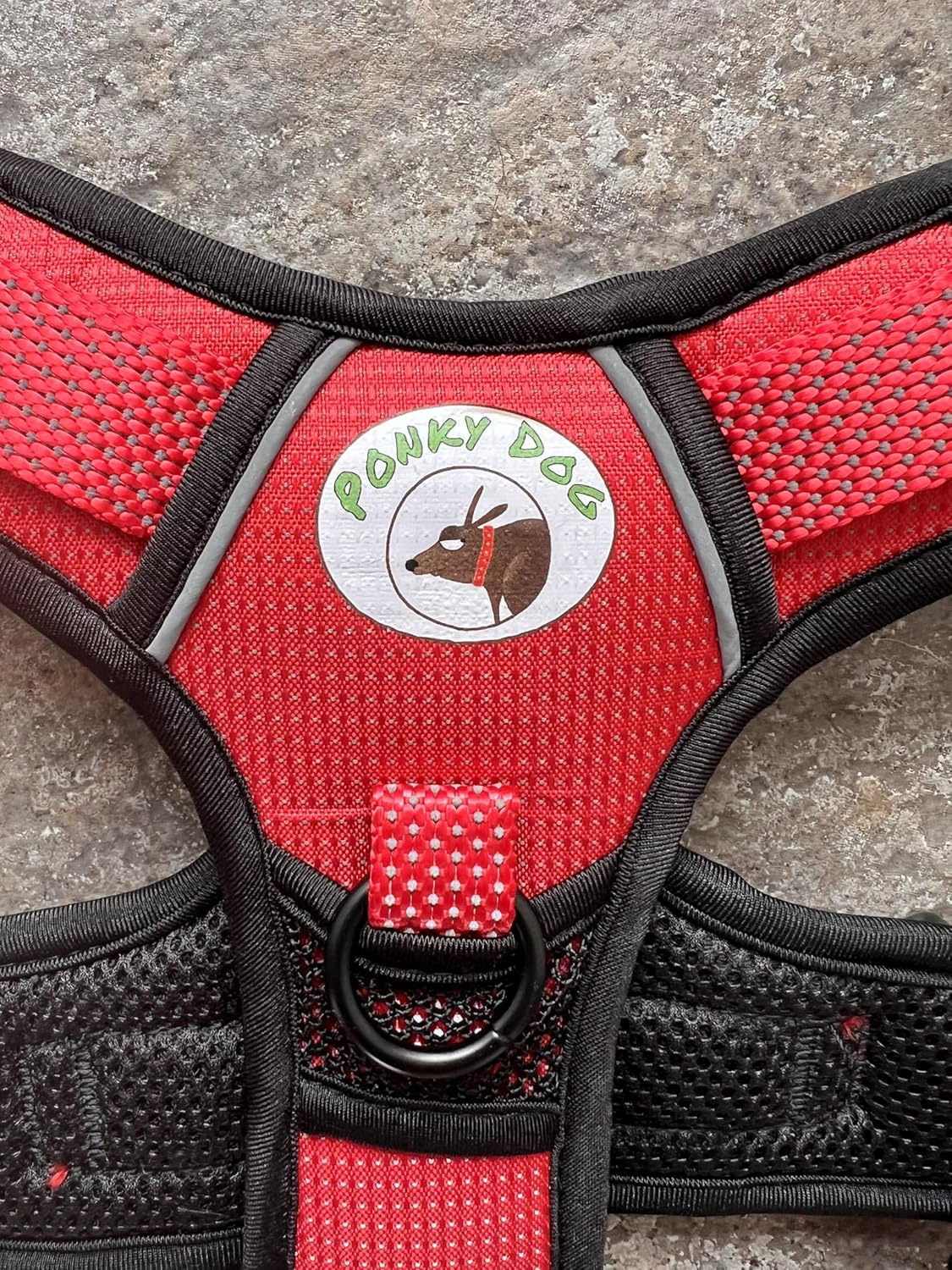 Close up of red dog harness with Ponky Dog logo and metal ring to attach lead